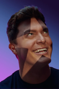 A close-up portrait of Zack Wickham with a star-shaped light projection, photographed by Ryan Grant for Queer Kentucky