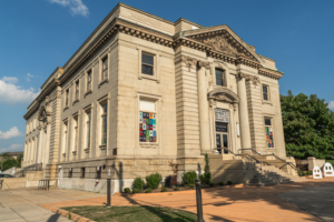 The Carnegie, a historic, light-colored brick arts center in Covington, with a large, columned archway and arched windows.