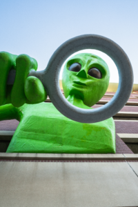 The alien named Clive is a large, 30-foot-tall art installation in Covington, Kentucky, located at the Midtown Garage parking lot. He is a green, fiberglass and foam alien who leans out of the garage with a giant magnifying glass, observing people below.