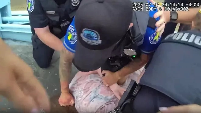Screenshot from police body camera footage showing multiple Covington police officers restraining a person on the ground during the July 17, 2025, Roebling Bridge protest. The image captures officers in uniform holding the individual facedown while attempting to control the situation. Photo Provided by Covington Police Department