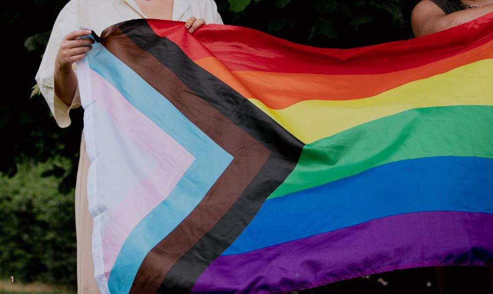 People hold a Progress Pride flag during an LGBTQ+ gathering as Kentucky lawmakers consider House Bill 553 affecting gender-affirming care.