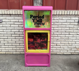 A bright pink Period Y’all pantry stocked with free menstrual products stands outside a building in Kentucky to provide public access to period supplies.